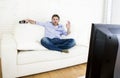 Man watching television at living room sofa with remote control smiling giving okay hand sign Royalty Free Stock Photo