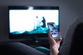 Man watching television and using smart tv remote control app. Royalty Free Stock Photo