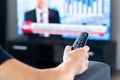 Man watching tv news program and sitting on couch home. Television remote control in hand. Politics, business or finance network. Royalty Free Stock Photo
