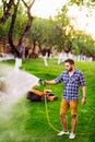 Man with water hose watering the grass, watering the lawn during summer evening