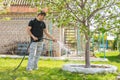 Man watering the fruit trees with a hose on a country site Royalty Free Stock Photo