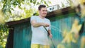 Man watering the garden from hose. Male spraying water on vegetables with a garden hose. A happy man with a hose takes care of the Royalty Free Stock Photo