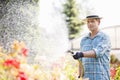 Man watering plants outside greenhouse