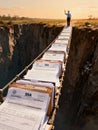 Man Waving From End of Precarious Bureaucratic Bridge Constructed Entirely from Stacks of SSA Documents Over a Deep Gorge Royalty Free Stock Photo