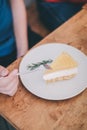 Man wear blue t-shirt sitting in coffee shop eating lemon cheesecake in white plate with folk