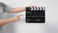 A man is hold black Clapper board or movie slate. wear gray t-shirt and it use in video production or cinema industry.It is white Royalty Free Stock Photo