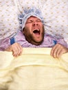 Man weared as baby in bed Royalty Free Stock Photo
