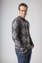 Man wearing argyle sweater, jeans and eyeglasses. Young men`s casual fall fashions clothing apparel styles.