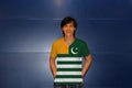 Man wearing Azad Kashmir flag on shirt and standing on the blue wall background