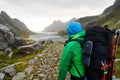 Young man with a backpacking hiking to a beautiful bay surrounded by mountains on Lofoten Islands in Norway Royalty Free Stock Photo