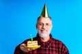 man wearing birthday hat with cake isolated on bright blue colour background, studio portrait Royalty Free Stock Photo