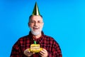 man wearing birthday hat with cake isolated on bright blue colour background, studio portrait Royalty Free Stock Photo