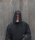 Man Wearing a Black Hooded Cape with Snow Falling Down