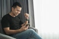 Man wearing black shirt looking at the mobile phone and happy