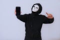 Man wearing black and white mask holding gadget in right hand Royalty Free Stock Photo