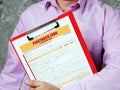 Man wearing blue business suit and showing financial document with written text PIGGYBACK LOAN Application Form. Blurred