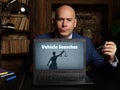 Man wearing blue business suit and showing laptop with written text Vehicle Searches