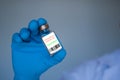A man wearing blue gloves holds a vaccine bottle, the concept of a vaccine lab experiment. Doctors are about to test coronavirus