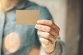 Man wearing blue jeans shirt and showing blank craft business card. Blurred background. Horizontal mockup