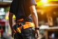 A man wearing a bright orange and black work vest stands ready for construction or manual labor