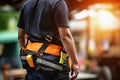 A man wearing a bright orange and black work vest stands ready for construction or manual labor