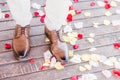 Man wearing brown leather shoes walking on rose petals