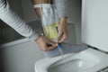 man emptyies his urine leg bag into the toilet