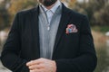 Man wearing a casual gray zipper jacket under a suit coat with bright, colorful pocket square