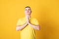 Man wearing casual t shirt begging and praying with hands together with hope expression on face very emotional and worried