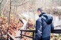 Man wearing a corona virus mask while walking outdoors in the nature in winter or autumn. Young person hiking the forest.