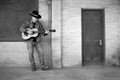 Man wearing cowboy hat and blue jeans playing acoustic guitar on factory loading dock Royalty Free Stock Photo