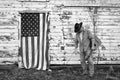 Man wearing cowboy hat and holding acoustic guitar standing in front of old barn with American flag Royalty Free Stock Photo