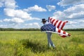 Man wearing cowboy hat running in beautiful grass field, American flag blowing in wind behind him