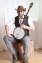 Man wearing cowboy leather hat and sunglasses holding banjo