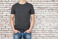 Man wearing dark grey t-shirt, brick wallbackground.