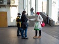 A man wearing a face mask and uniform distributes newspapers to people exiting the doors of a subway station