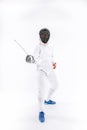 Man wearing fencing suit practicing with sword against gray