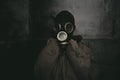 A man wearing a gas mask staying in the dark in a dilapidated building