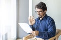 Man wearing glasses on a chair holding paper document. Royalty Free Stock Photo