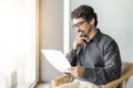 Man wearing glasses on a chair holding paper document. Royalty Free Stock Photo