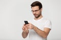 Man wearing glasses pose on grey background using mobile phone Royalty Free Stock Photo