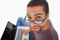 Man wearing glasses sitting on floor using laptop and smiling up Royalty Free Stock Photo