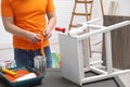 Man wearing gloves near can of white paint and bekvam at black wooden table indoors, closeup Royalty Free Stock Photo