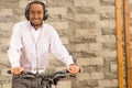 Man wearing grey office pants, white red business shirt standing by bicycle holding mobile phone, headphones on head Royalty Free Stock Photo