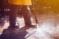 A man wearing gum boots and a yellow waterproof jacket cleaning the stone Royalty Free Stock Photo