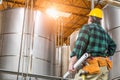 Man Wearing Hard Hat Looking Up At Large Industrial Tanks Royalty Free Stock Photo