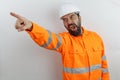 Man wearing hardhat and reflecting jacket showing and pointing with finger screaming and shouting anger rage.