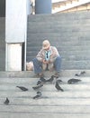 Oil Painting of Retired Old Man Sitting on Steps Feeding Pigeons, Looking at His Phone