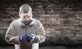 Man Wearing Hazmat Suit, Protective Gas Mask and Goggles Against Brick Wall