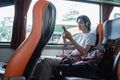 a man wearing headphones while listening music from a handphone while sitting by the window Royalty Free Stock Photo